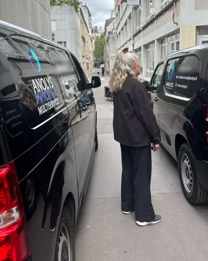 Deux utilitaires noirs au logo ANOLYS Multiservices garés dans une rue, une personne de dos entre les deux